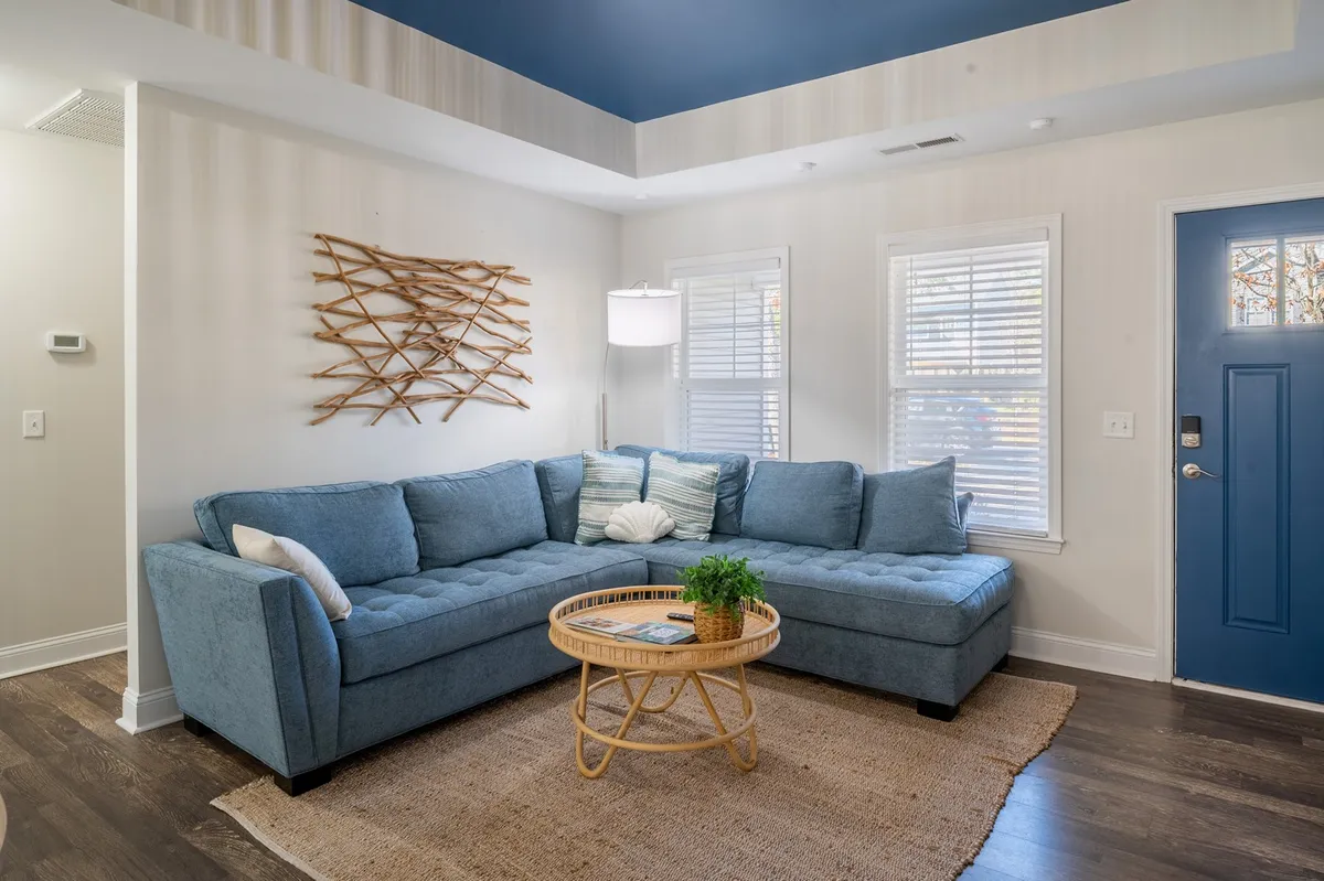 A cozy, inviting living space featuring a blue sectional sofa and a rattan coffee table, with decorative wall art adding a touch of personality. Natural light streams in, creating a bright setting perfect for relaxing or socializing after a day of adventure.