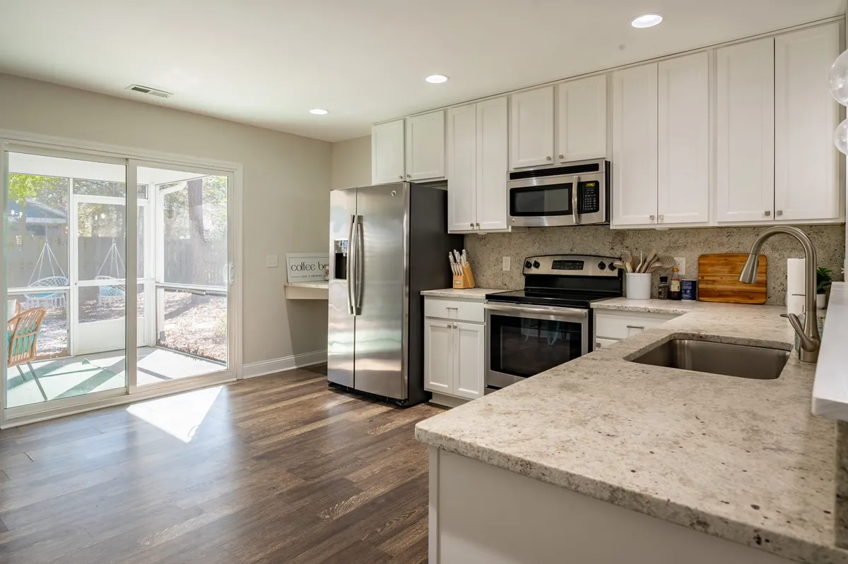 A modern kitchen with a bright island, stainless steel appliances, and large windows bringing in natural light. The space is ideal for cooking, entertaining, and preparing meals to share with friends and guests.