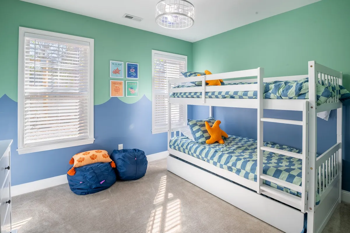 A colorful bunk bed setup with playful wall art and vibrant cushions, evoking a sense of fun and creativity. The arrangement is clearly child-centered, inviting playtime, reading, and cozy evenings.